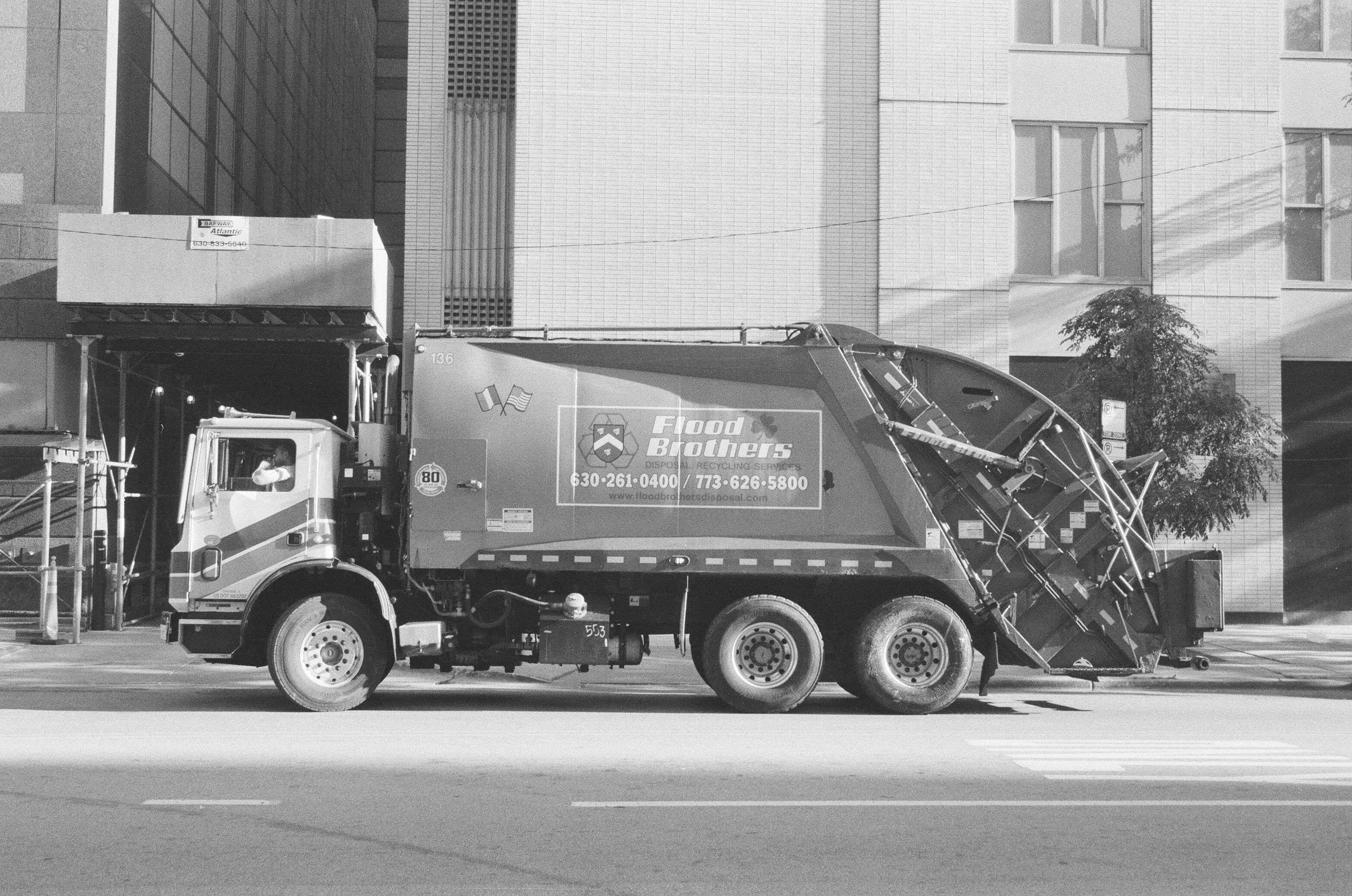 A black and white profile shot of a garbage truck